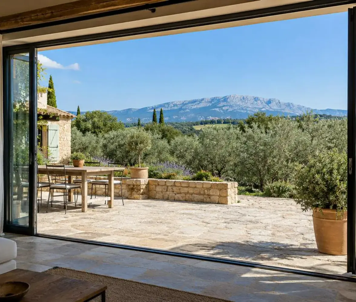 Baie vitrée coulissante ouverte sur la terrasse d'une bastide du pays d'Aix, Sainte-Victoire au loin