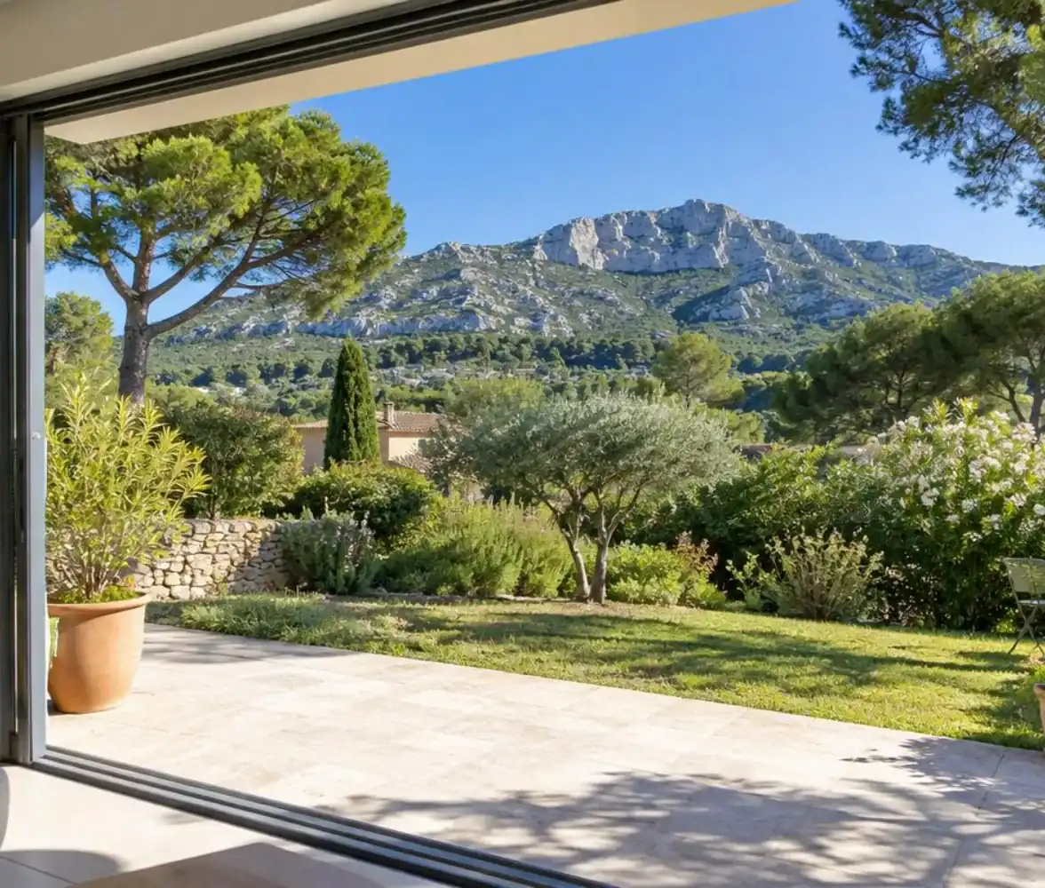 Baie vitrée coulissante ouverte sur le jardin d'une maison d'Aubagne, massif du Garlaban en arrière-plan